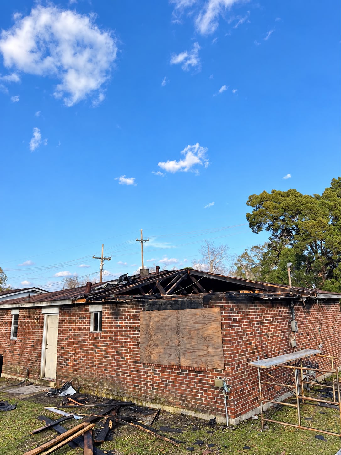 Brick home with damaged roof and exposed framing before repair